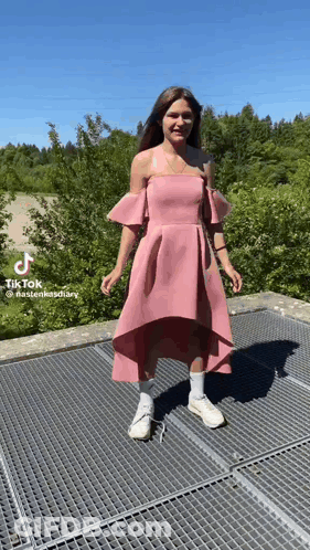 Woman In Pink Dress And White Sneakers On Metal Fence GIF