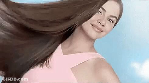 Woman In Pink Dress Holding Hair In Air Smiling GIF
