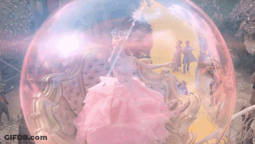 Woman In Pink Dress Holding Wand In Bubble GIF