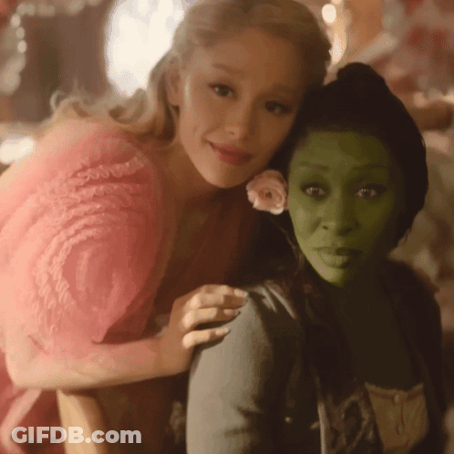 Woman In Pink Dress Hugging Woman With Green Face GIF