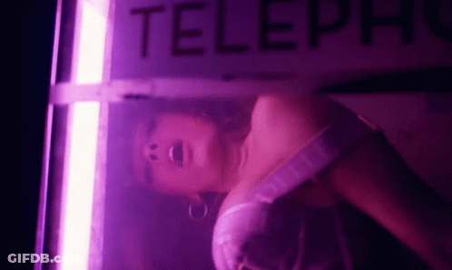 Woman In Pink Dress Laying In Telephone Booth With Purple Light GIF