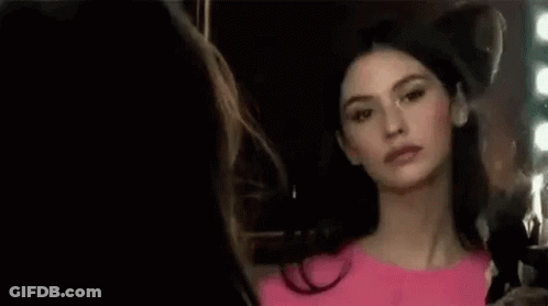 Woman In Pink Dress Looking In Mirror GIF