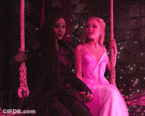 Woman In Pink Dress Sitting Next To Woman In Black Dress On Swing GIF