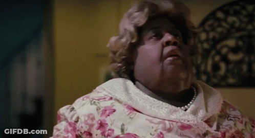 Woman In Pink Floral Dress And Pearls On Bed GIF