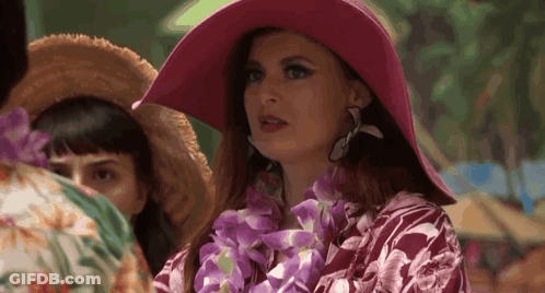 Woman In Pink Hat And Lei Standing In Crowd GIF