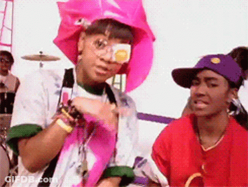 Woman In Pink Hat And Sunglasses Next To Woman In Red Shirt GIF