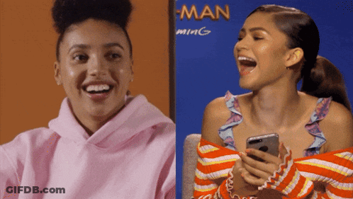 Woman In Pink Hoodie Laughing Next To Woman In Orange Sweater GIF