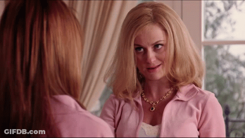 Woman In Pink Jacket And Necklace Admiring Reflection GIF