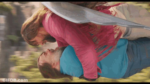 Woman In Pink Jacket Holding Man In Blue Shirt GIF