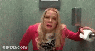 Woman In Pink Jacket Holding Toilet Paper In Public Restroom GIF