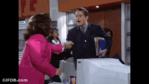 Woman In Pink Jacket Shaking Hands With Man In Suit GIF
