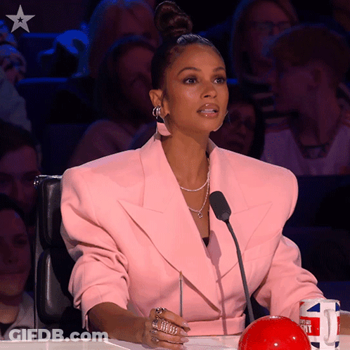 Woman In Pink Jacket Sitting In Front Of Microphone And Red Ball GIF