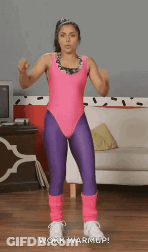Woman In Pink Leotard And Purple Leggings Standing In Front Of Couch GIF