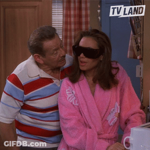 Woman In Pink Robe And Sunglasses Beside Man In Striped Shirt TV Land Logo GIF