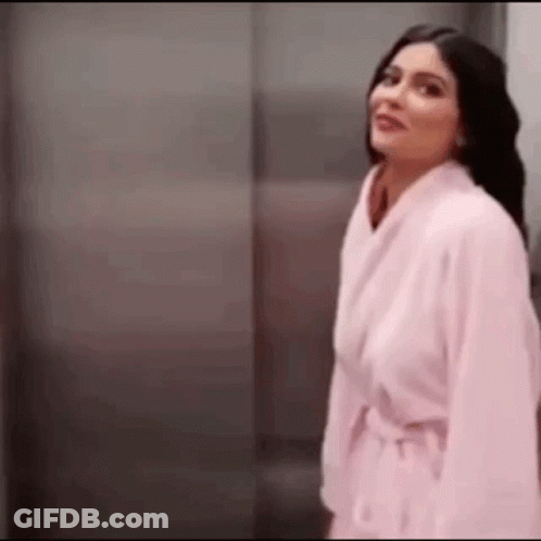 Woman In Pink Robe In Front Of Elevator GIF