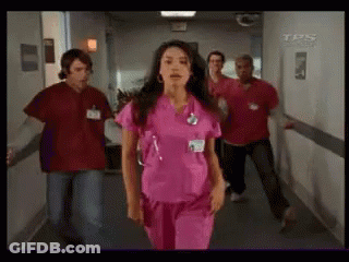 Woman In Pink Scrubs Walking Down Hallway GIF