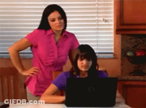 Woman In Pink Shirt And Girl In Purple Shirt Looking At Laptop GIF
