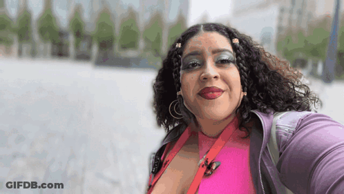 Woman In Pink Shirt And Purple Jacket Smiling GIF