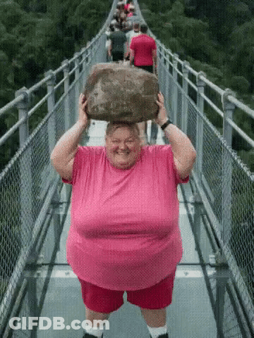 Woman In Pink Shirt Carrying Rock On Bridge GIF
