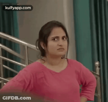 Woman In Pink Shirt Hands On Hips By Staircase GIF