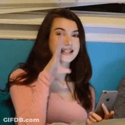 Woman In Pink Shirt Holding Phone Making Funny Face GIF