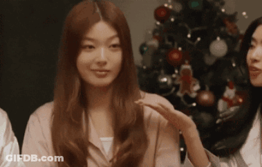 Woman In Pink Shirt In Front Of Christmas Tree GIF
