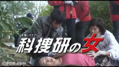 Woman In Pink Shirt Laying On Ground Surrounded By People With Chinese Writing GIF