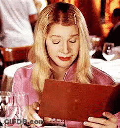 Woman In Pink Shirt Looking At Menu In Restaurant GIF