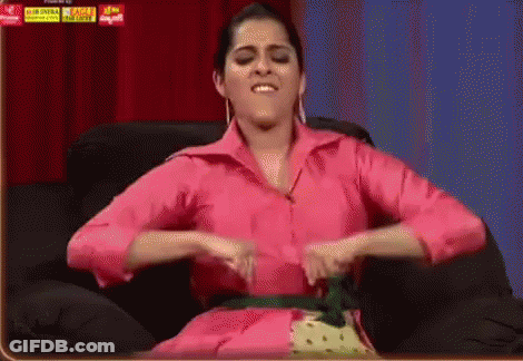 Woman In Pink Shirt Sitting With Hands On Stomach GIF
