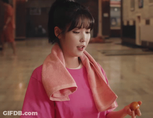 Woman In Pink Shirt Smiling Holding Hair In Bun GIF