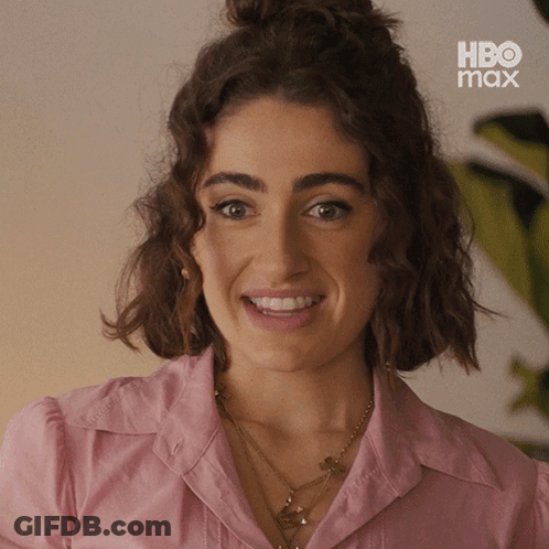 Woman In Pink Shirt Smiling In Front Of HBO Max Sign GIF