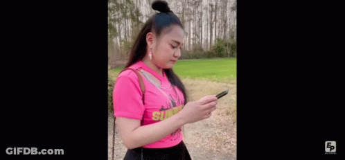 Woman In Pink Shirt Standing On Dirt Road In Field GIF
