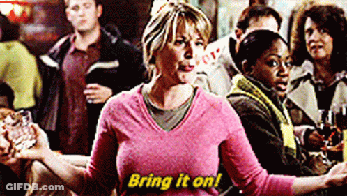 Woman In Pink Sweater Saying Bring It On In Yellow GIF