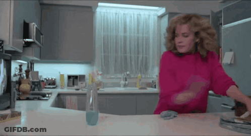 Woman In Pink Sweater Standing In Kitchen GIF
