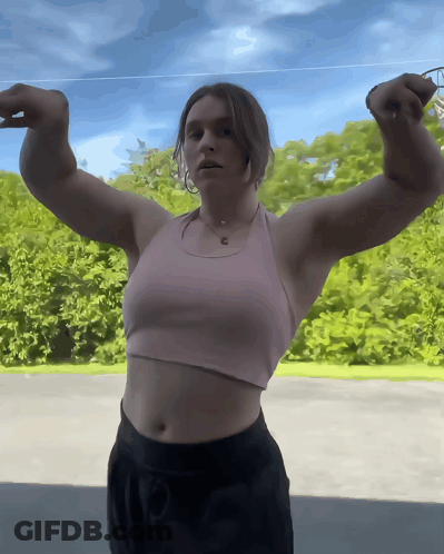 Woman In Pink Tank Flexing Arms GIF
