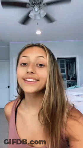 Woman In Pink Tank Top Smiling In Front Of Ceiling Fan GIF