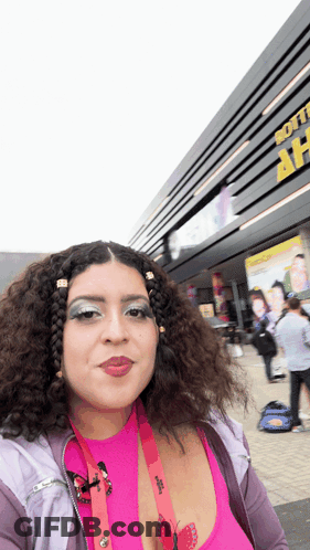 Woman In Pink Top In Front Of Soft Building GIF