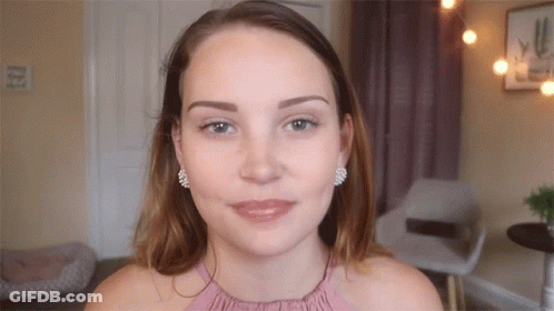 Woman In Pink Top With Earrings Looking At Camera GIF