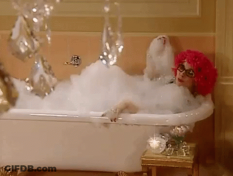 Woman In Pink Wig Lying In Bubble Bath GIF