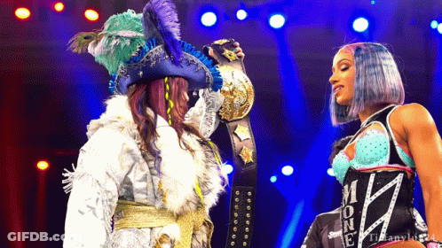 Woman In Pirate Costume Holding Championship Belt Next To Another Woman GIF