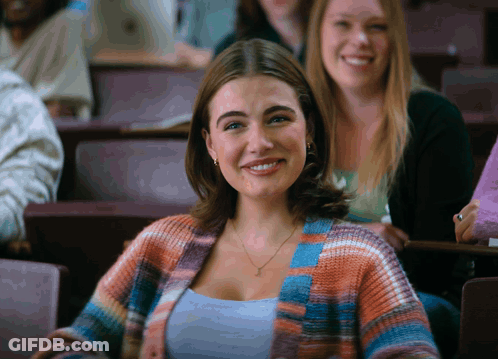 Woman In Plaid Cardigan Smiling In Classroom GIF