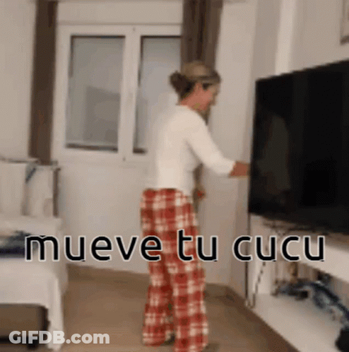 Woman In Plaid Pants Standing Before TV Saying Mueve Tu Cucu GIF