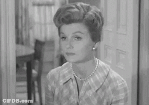 Woman In Plaid Shirt And Pearls Sitting By Door GIF
