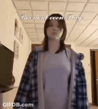 Woman In Plaid Shirt And White Shirt In Hallway GIF