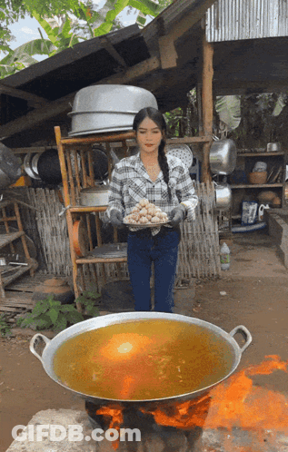 Woman In Plaid Shirt Holding Tray Near Large Pot GIF