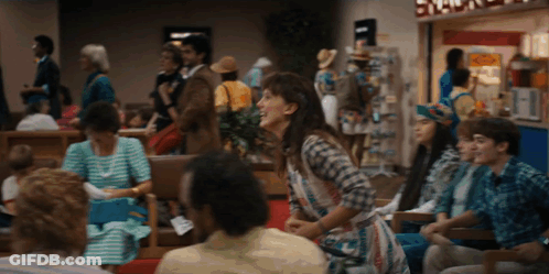 Woman In Plaid Shirt Laughing In Crowded Area GIF