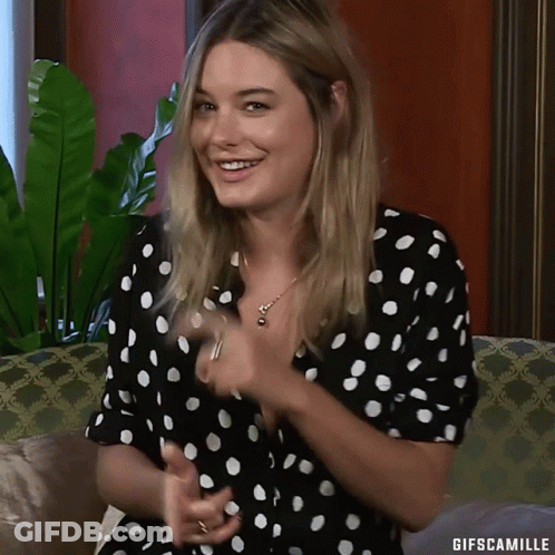 Woman In Polka Dot Dress Smiling On Couch GIF