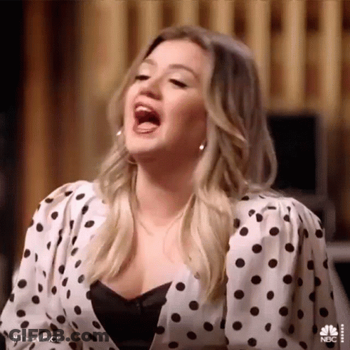 Woman In Polka Dot Shirt Singing With Mouth Open GIF