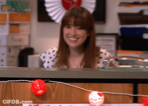 Woman In Polka Dot Shirt Smiling Behind Desk GIF