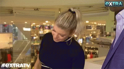 Woman In Ponytail Facing Man In Suit Extratv Sign GIF